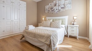 Une chambre à coucher comprenant un lit, des tables de chevet, une armoire et des œuvres d’art murales.