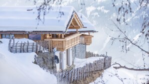 A wooden chalet with a balcony, surrounded by snow and a wooden fence. - Holiday Home "Chalet Henne-Hochgruberhof" in Idyllic Mountain Location with Own Sauna (Mühlwald)