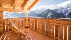 A wooden deck with a bench, wooden railings, and a mountain view.