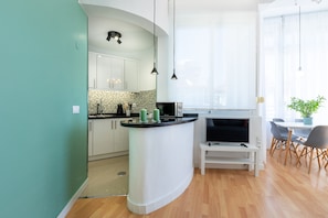 Una cucina moderna con mobili bianchi, un'isola dalla forma curva e un'area pranzo con tavolo e sedie.