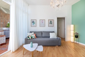 Un soggiorno moderno con un divano grigio, un tavolino bianco e un lampadario.