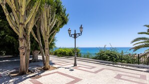 Un sendero pavimentado con diseño, una farola y vista al mar.
