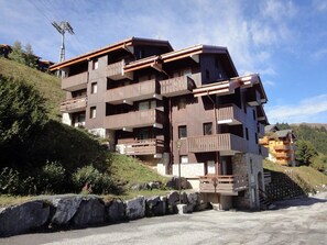 Um hotel com vários andares e varandas, localizado numa encosta com céu limpo.