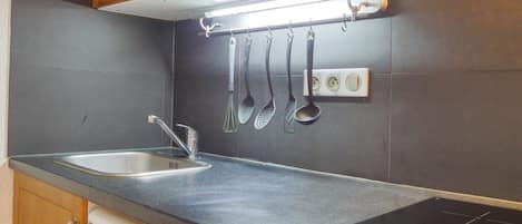 A kitchen with a stainless steel sink, a microwave above it, and a black induction cooktop.