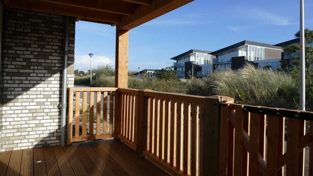 Una terraza de madera con un muro de ladrillo y vistas a edificios modernos al fondo.