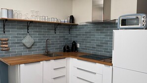 Una cocina moderna con armarios blancos, encimera de madera, horno empotrado y salpicadero de baldosas grises.
