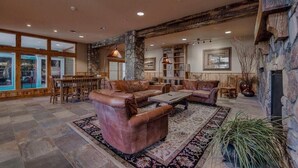 A spacious living area with leather sofas, a coffee table, and a stone fireplace. - River Run Village Walk To Gondola Pool Hot Tubs Restaurants and Shops DELUXE (Keystone)