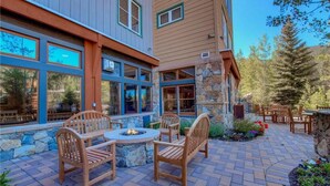 A patio with a fire pit, wooden chairs, and a stone wall. - River Run Village Walk To Gondola Pool Hot Tubs Restaurants and Shops DELUXE (Keystone)