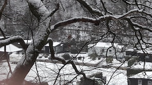 Paisaje nevado con árboles desnudos y una vista distante de una zona residencial con casas y una escalera que conduce a un edificio.