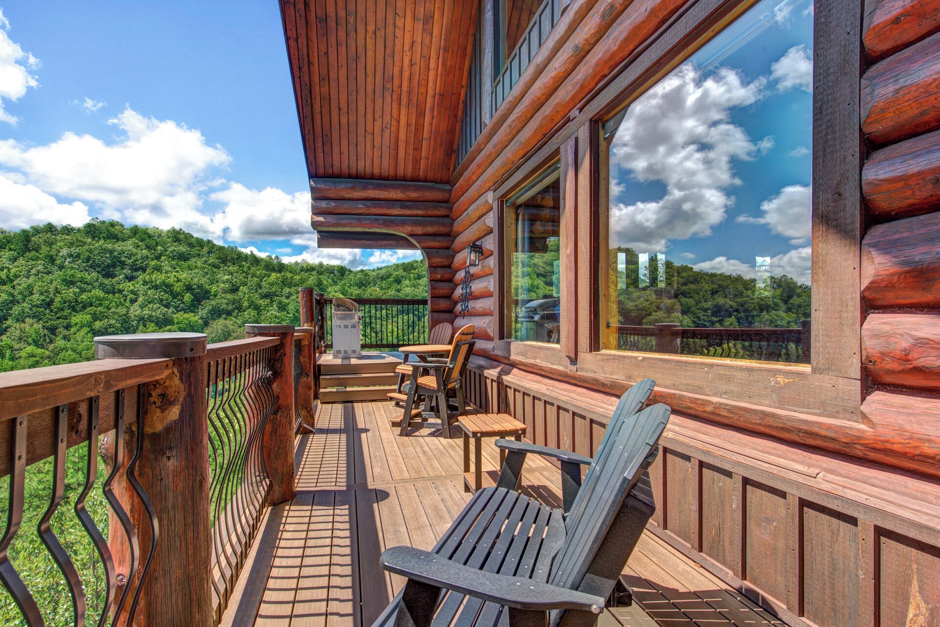 A wooden deck with outdoor seating and a view of a forested hillside.