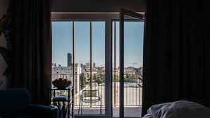A hotel room with a large sliding glass door leading to a balcony with a city view. - Superbude Wien Prater (Vienna)