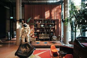 Una stanza con una grande statua di astronauta, una libreria e diverse poltrone.