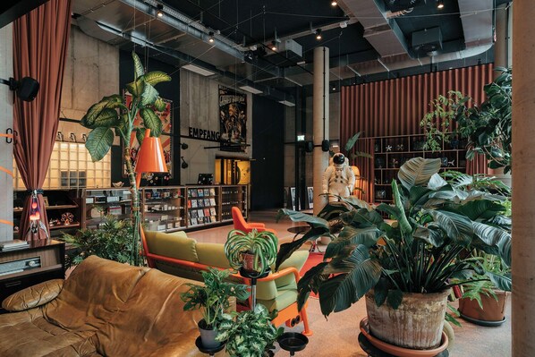 Un intérieur moderne avec un canapé, une bibliothèque et une grande plante en pot.