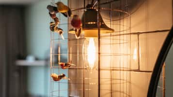A birdcage with a light bulb and several birds inside.
