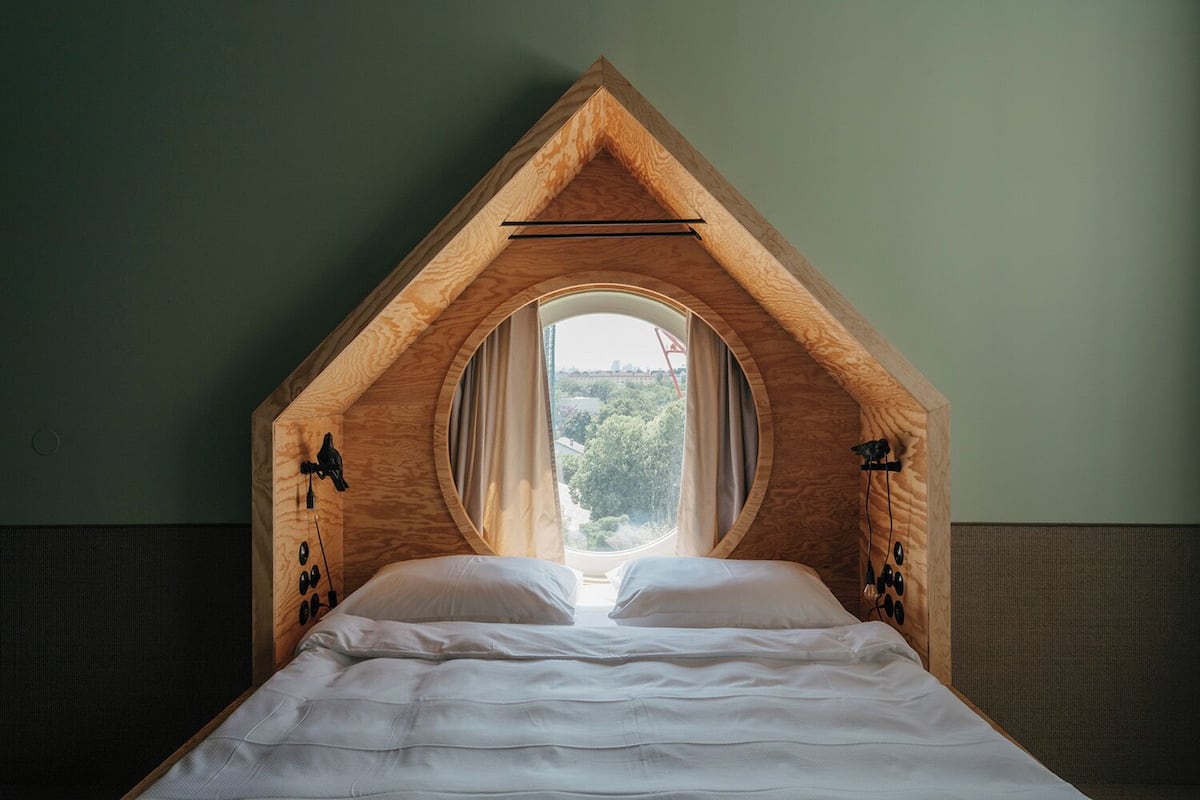 A bedroom with a sloped ceiling and a large circular window.