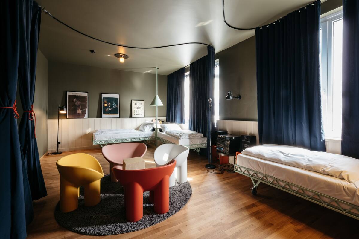 A modern bedroom with two beds, a desk, and a chair.