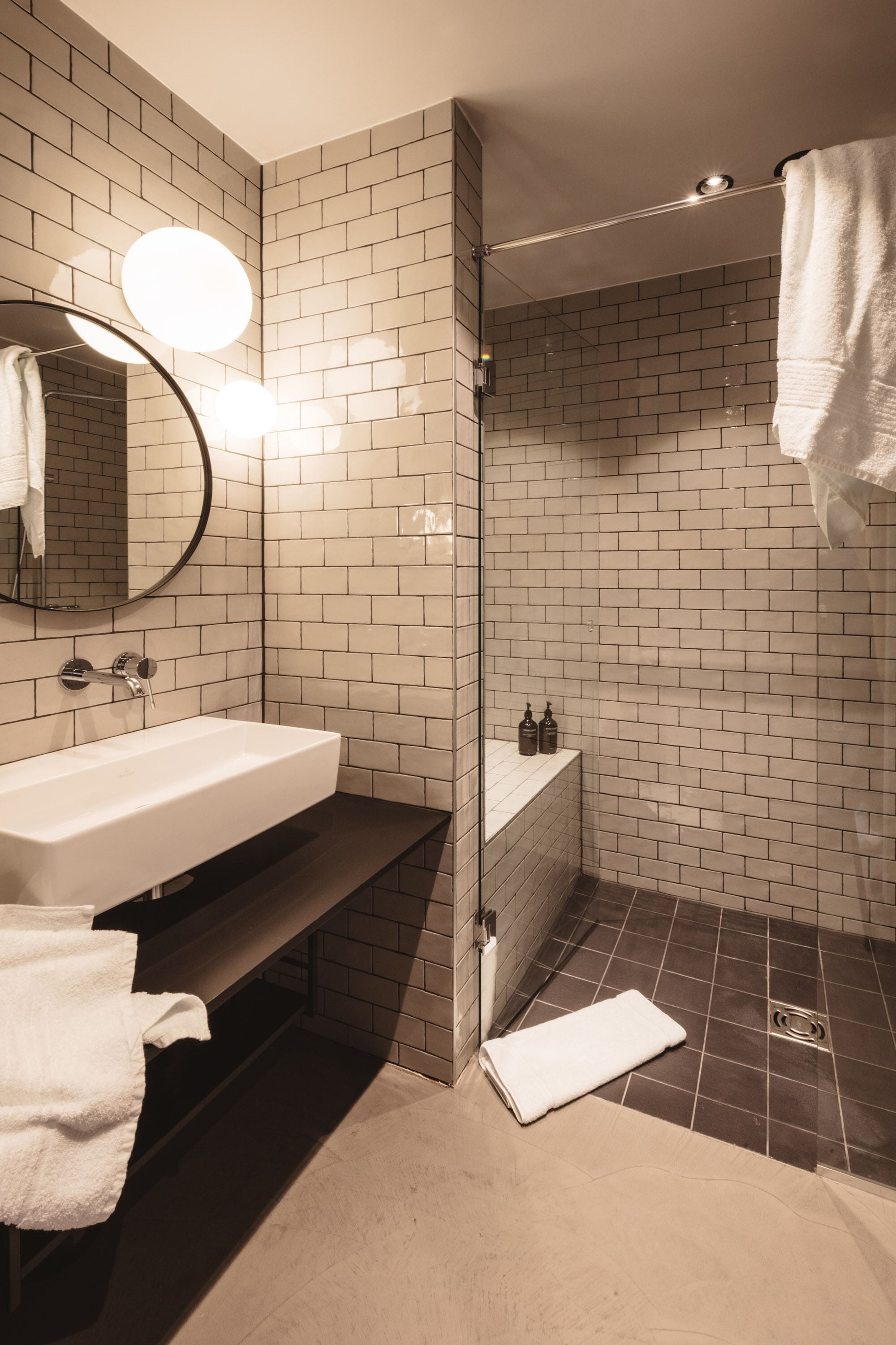 A modern bathroom with a white sink, mirror, and tiled walls.