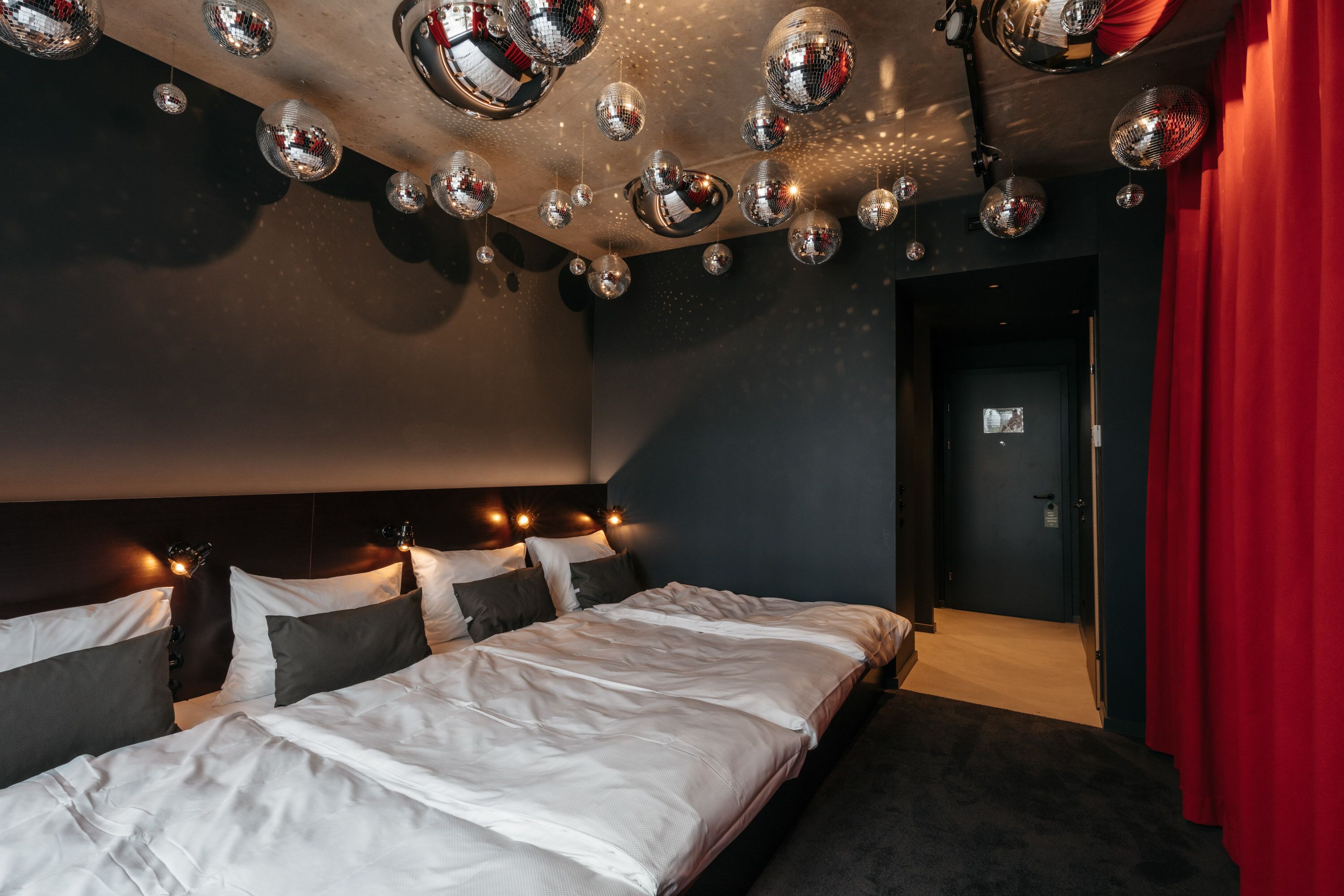 Una habitación de hotel con una cama grande, un cabecero oscuro y varios globos de discoteca en el techo.