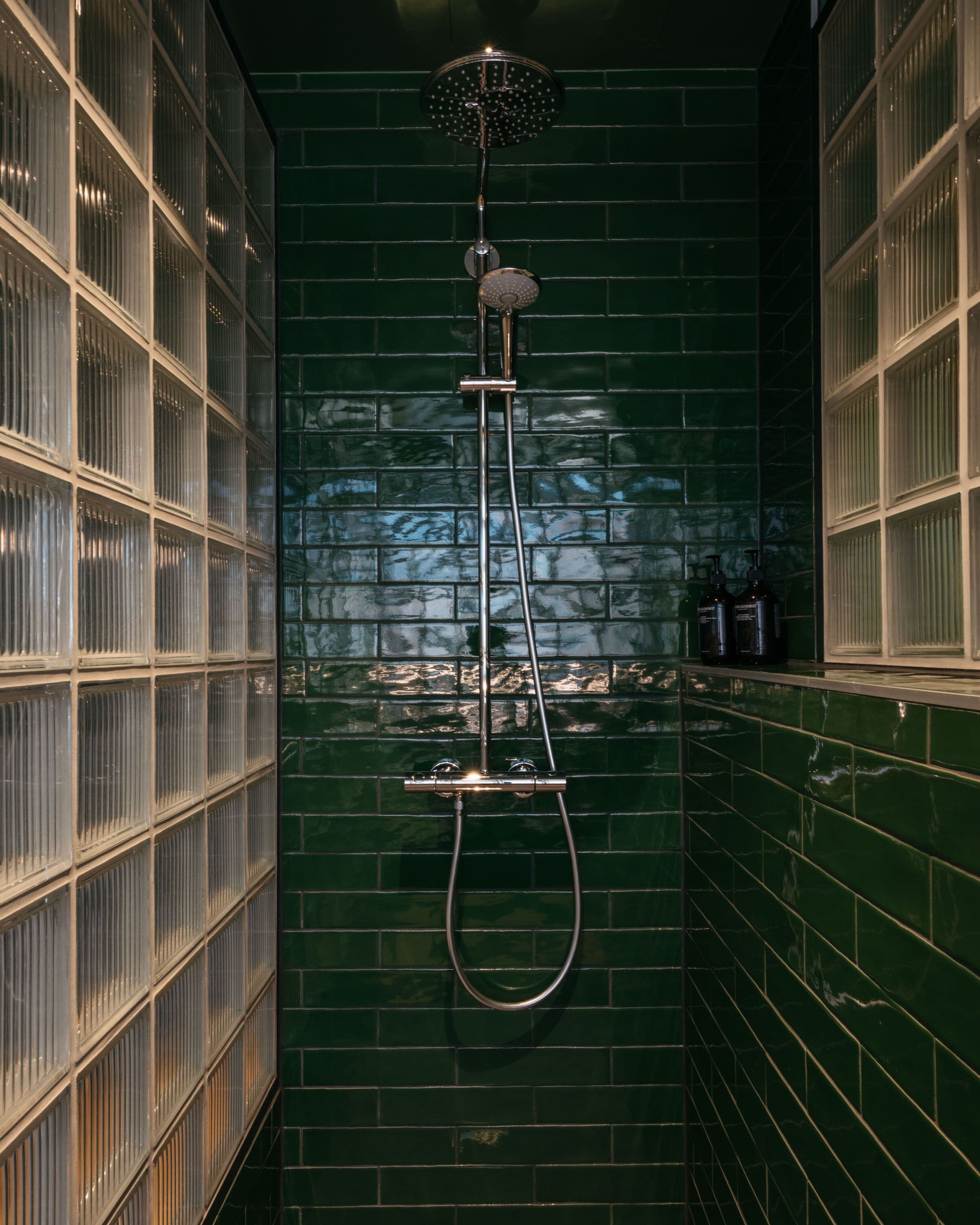 Un espace douche étroit doté d’une porte en verre, d’un pommeau de douche et d’un flexible de douche.