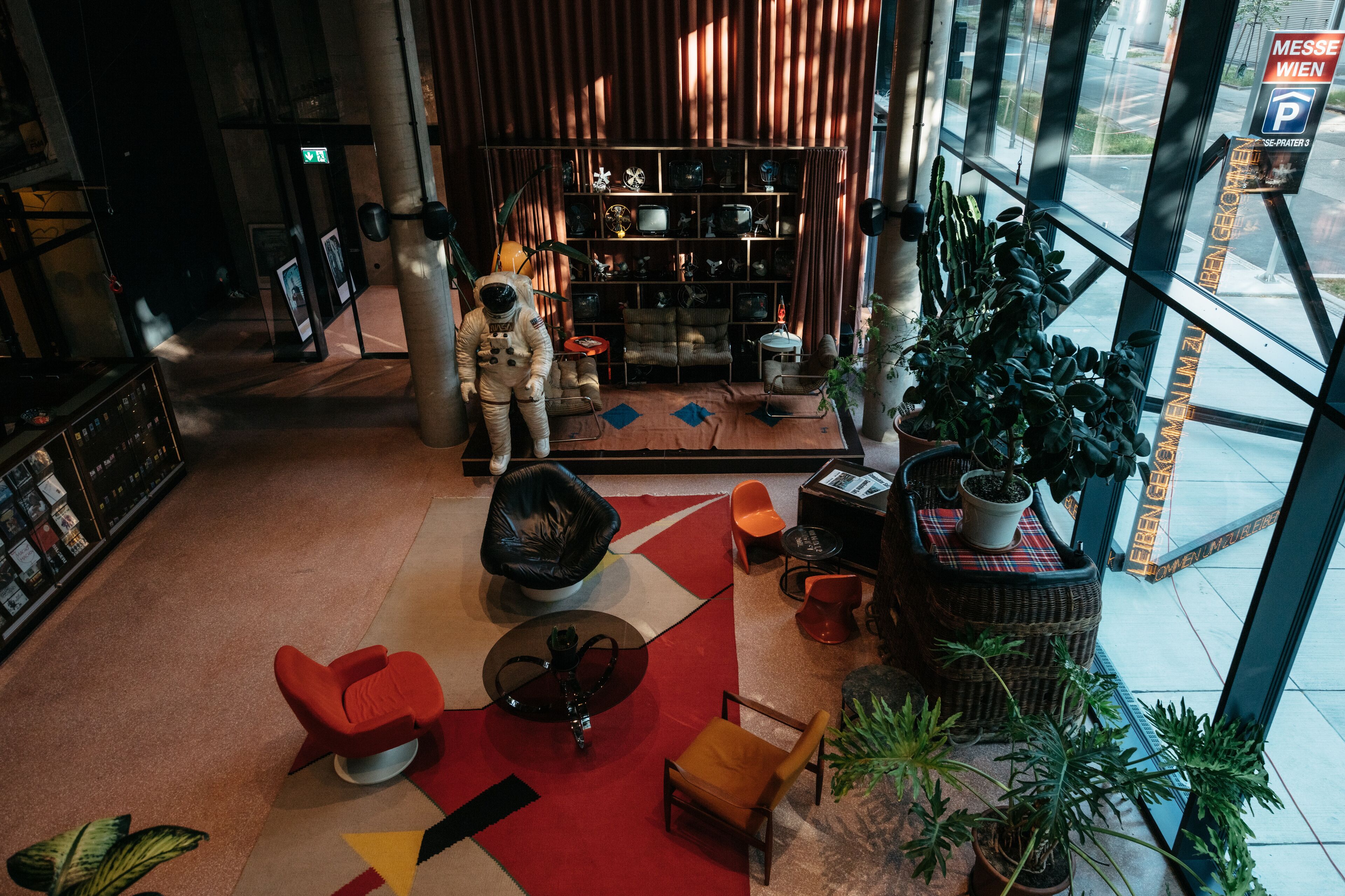 A modern lobby with a large bookshelf, a mannequin astronaut, and various seating options.