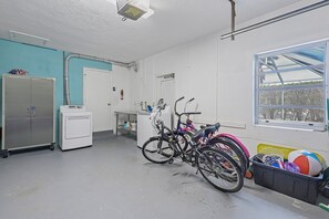 A laundry room with a washing machine, dryer, and bicycle storage. - Home on Water | Pool/Lanai Kitchen/Walk to Beach (Marco Island)