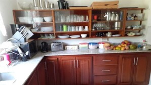 A kitchen with wooden cabinets, a countertop with various kitchen items, and a fruit bowl. - Breathtaking View Villa Tranquil Vibe (Falmouth)