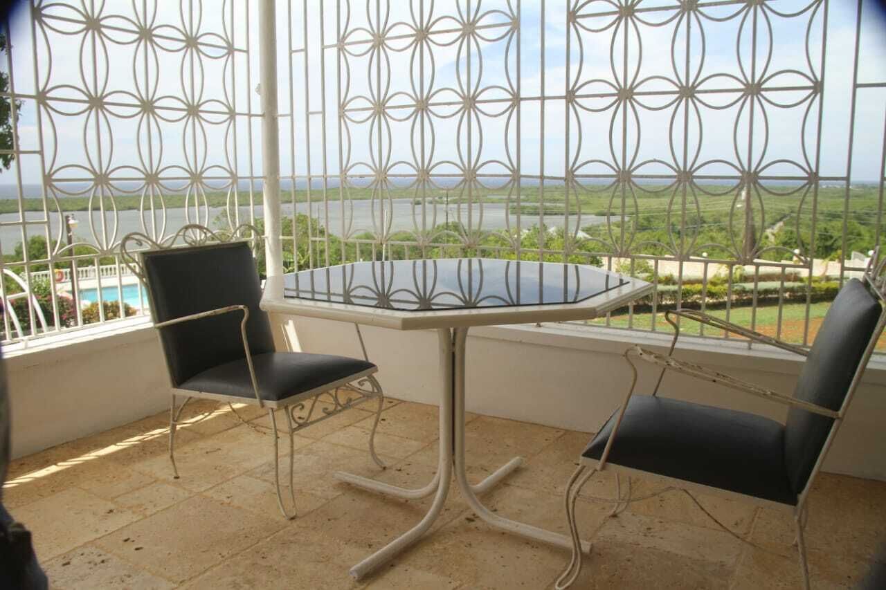 Ein Balkon mit Tisch und zwei Stühlen, der einen schönen Blick auf ein Gewässer und grüne Landschaft bietet.