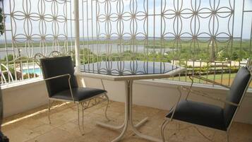 Ein Balkon mit Tisch und zwei Stühlen, der einen schönen Blick auf ein Gewässer und grüne Landschaft bietet.