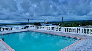 A rectangular swimming pool with a white balustrade, surrounded by a tiled deck. - Breathtaking View Villa Tranquil Vibe (Falmouth)