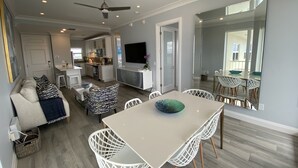 Una cocina moderna con armarios blancos, un comedor con mesa y sillas blancas, y un ventilador de techo.