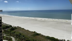 Vista a la playa desde un balcón, cielo despejado y mar tranquilo.