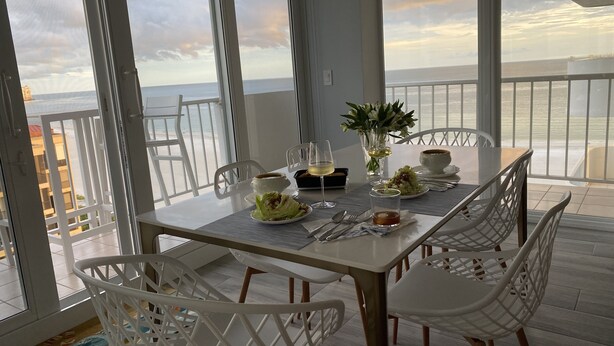 Un comedor con una mesa dispuesta para dos personas, con vista a la playa.