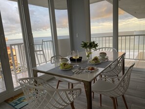 A dining area with a table set for two, overlooking a beach. - Paradise awaits you - 2/2 Penthouse Condo-Spectacular Beachfront and City Views (Marco Island)