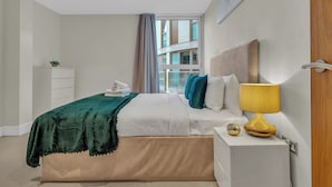 A modern bedroom with a bed, bedside table, and a view of the outside.