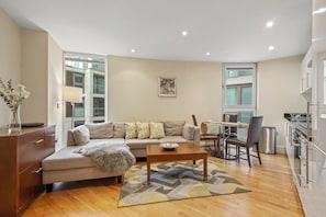 A modern living room with a sofa, coffee table, and dining area.