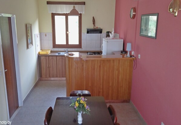 Une cuisine compacte avec des meubles en bois, un évier encastré et un coin repas comprenant une table et des chaises.