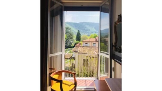 Ein Zimmer mit großem Fenster, einem Sessel und einem Tisch.