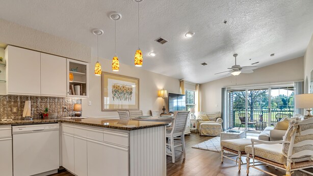 Una cocina amplia con una isla central, muebles de cocina blancos e iluminación colgante.