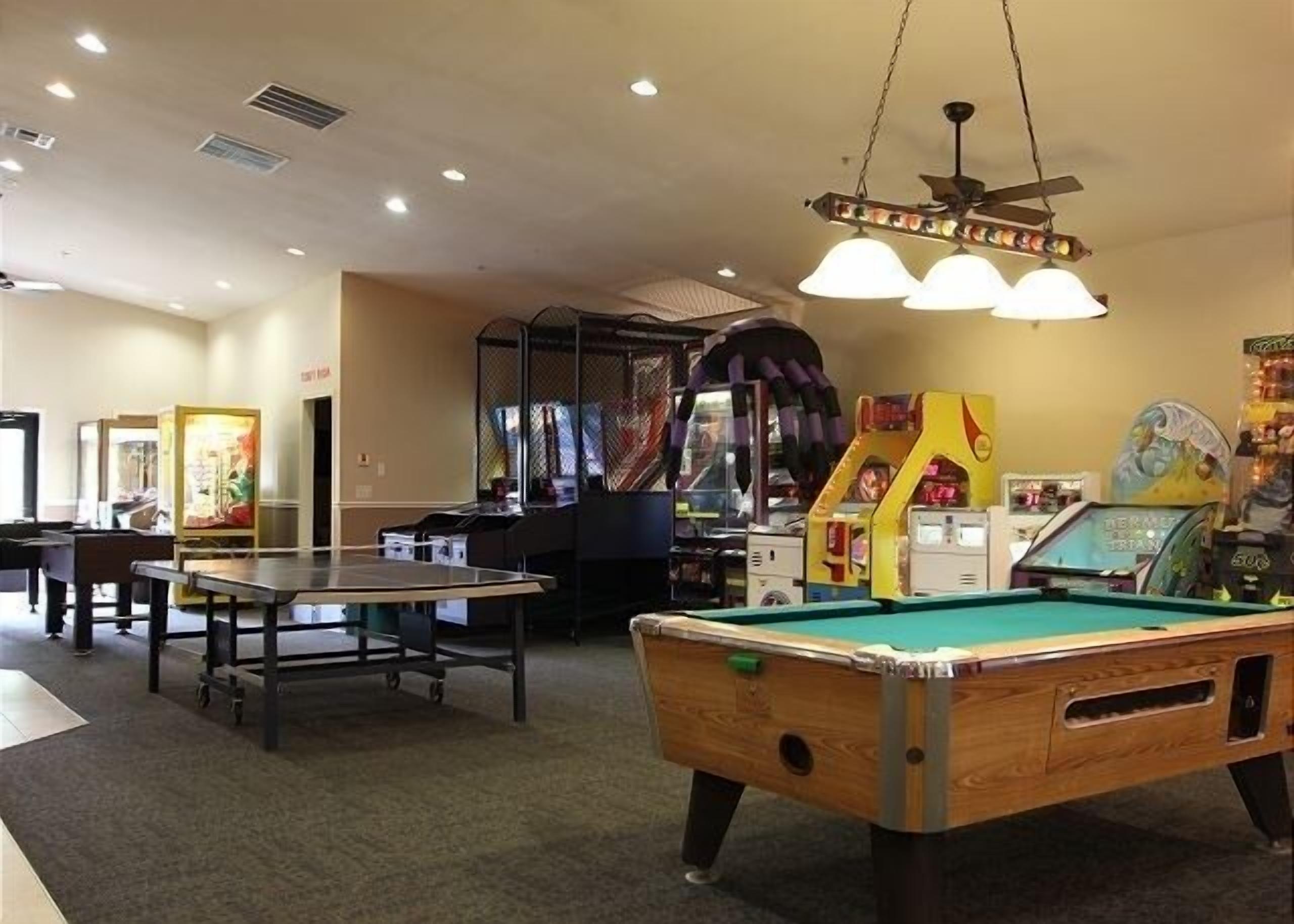 Une table de billard, une table de jeu de flipper et des jeux d’arcade dans un espace de loisirs.