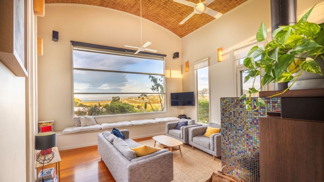 A living room with a large window, a ceiling fan, a fireplace, and a seating area.