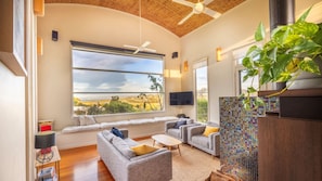 A living room with a large window, ceiling fan, and a view of the outdoors.
