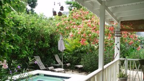 A covered outdoor area with a pool, lounge chairs, and potted plants.