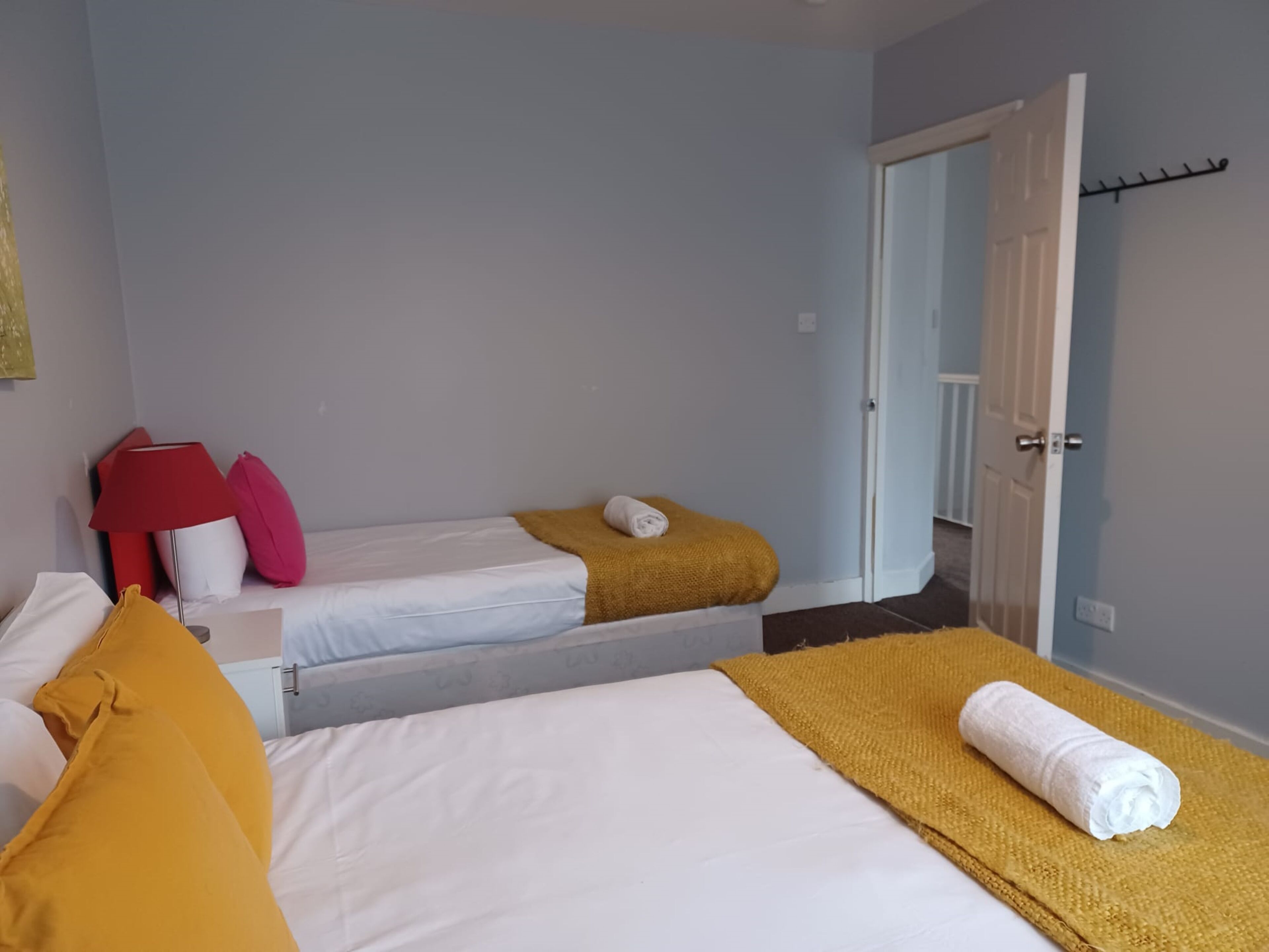 Ein Hotelzimmer mit zwei Betten, einer roten Lampe und einer Tür zu einem anderen Raum.