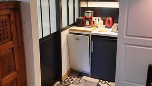 Et kompakt køkken med et køleskab, en kaffemaskine og en brødrister.