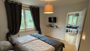 Een slaapkamer met een bed, een televisie en uitzicht op een balkon.