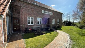 A brick building with a sign reading "HANEBURG" and a paved pathway leading to the entrance.