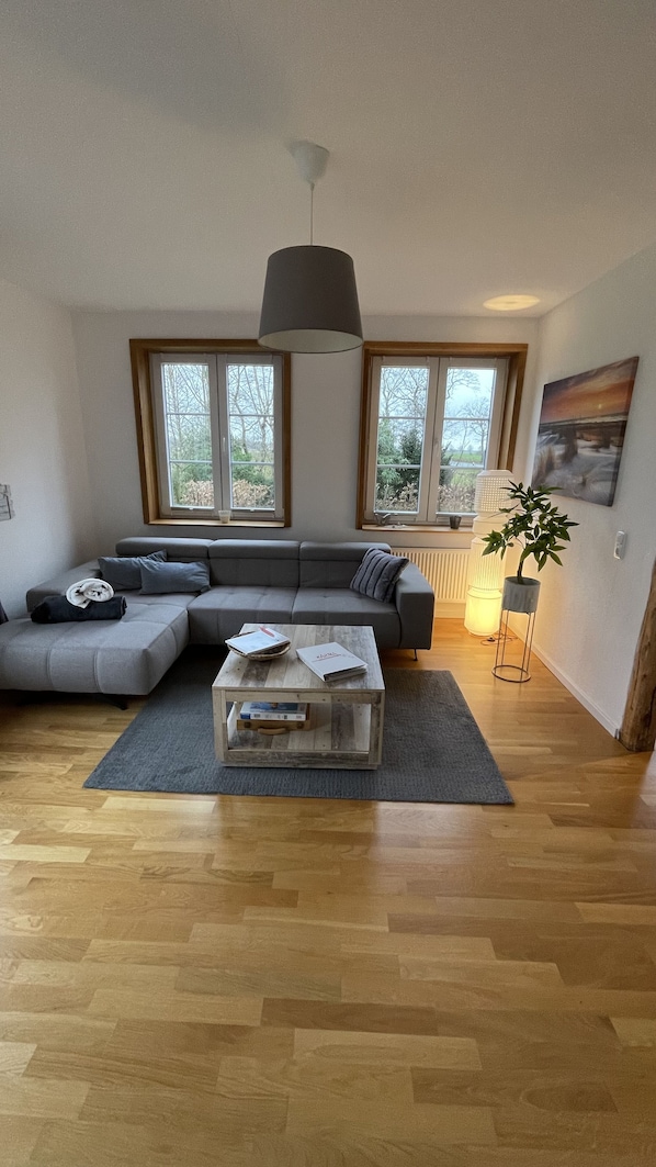 A modern living room with a grey sectional sofa, a wooden coffee table, and a floor lamp.