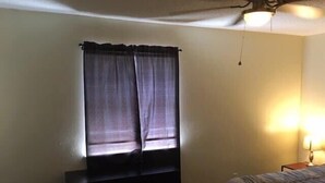Ein Schlafzimmer mit Bett, Schminktisch und einem Fenster mit Vorhängen.