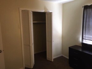 Ein Zimmer mit Schrank, Kommode und einem Vorhang vor dem Fenster.