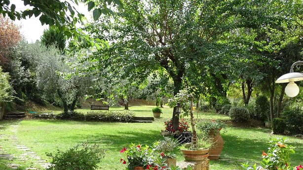 A garden with a stone pathway, benches, and potted plants. - Two-room apartment barn in farmhouse with swimming pool (Scandicci)